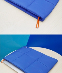 Detail view of Klein blue laptop sleeve with puffer texture and orange drawstring closure