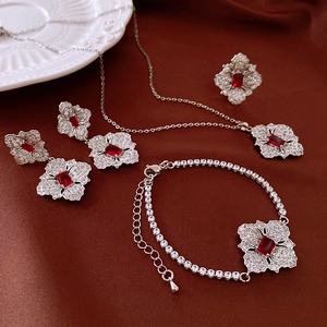 Detailed view of silver zircon flower jewelry set with red rubies on silk fabric