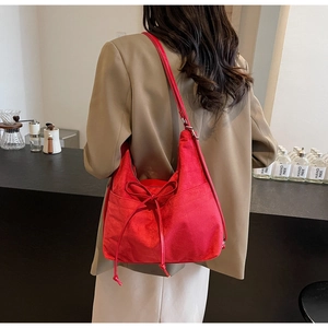 Detail of red faux suede casual tote bag with drawstring bow on a model in a cafe