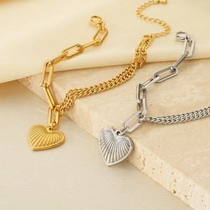Detail of 18K gold and silver mixed chain bracelet with a striped heart pendant
