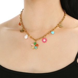 Detail of gold necklace with colorful flower, butterfly, heart and pearl charms on model