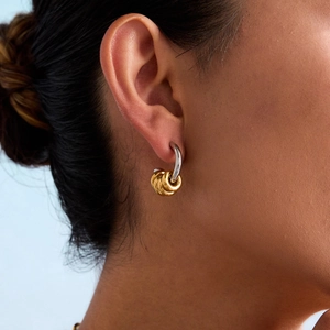 Close-up of dual-tone gold and silver C-shaped hoop earrings on a model's ear