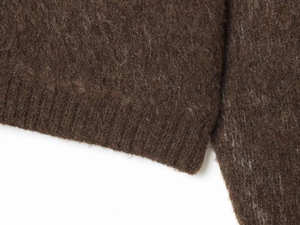 Macro shot of dark brown knit sweater showing hairy texture and ribbed cuff details