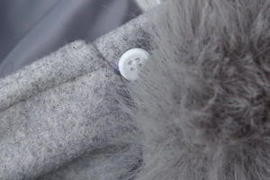 Vue macro détaillée de la texture en peluche grise et du bouton blanc à quatre trous