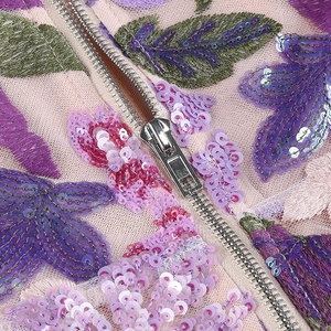 Detailed macro shot of premium purple and pink sequin embroidery with a metal zipper