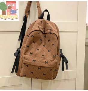 Detail of brown corduroy backpack featuring black bow patterns and diamond stitching