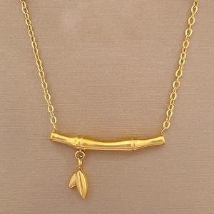 Macro shot of gold bamboo pendant with delicate leaf charms on a premium O-chain necklace