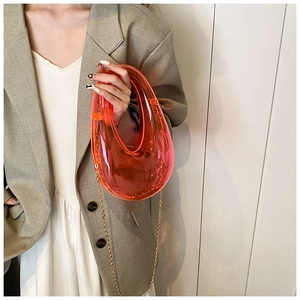 Detail showing transparent pink acrylic U-shaped handbag with elegant gold chain strap