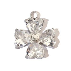 Macro shot of silver clover pendant with heart-shaped zircon stones on white background