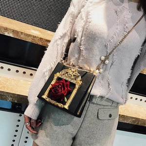 Detail of floral box crossbody bag with gold frame and red rose on model outfit