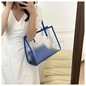 Detailed view of a transparent PVC tote bag with blue trim and colorful metal rivets