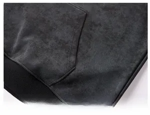 Detail of dark gray hoodie showing kangaroo pocket and ribbed hem with fleece texture