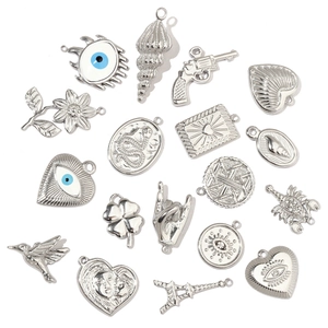 Macro detail of silver stainless steel DIY jewelry pendants including heart and snake charms