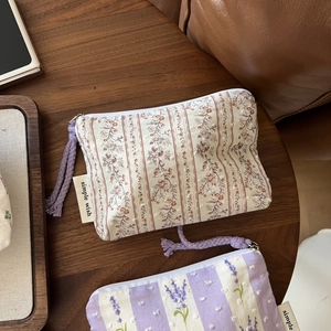 Detailed view of floral cotton mini pouches with textured dots and purple zipper pulls