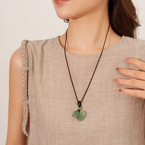 Detailed view of long braided rope necklace with vintage green heart pendant for women