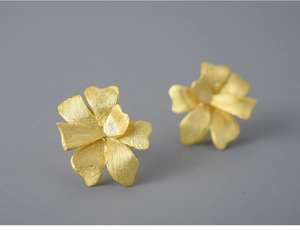 Detailed macro view of gold petal stud earrings with fine brushed metal texture