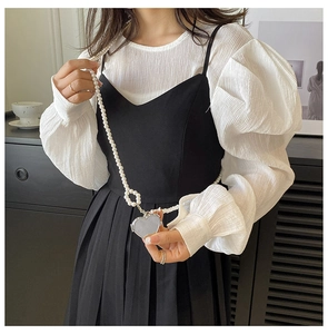 Silver heart-shaped mini bag with elegant pearl chain strap shown on model's shoulder