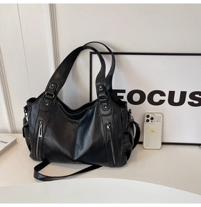 Large black vintage tote bag with decorative rivets and zipper on a white surface