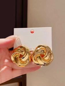 Detail view of gold twisted metal flower earrings showing the S925 silver post texture