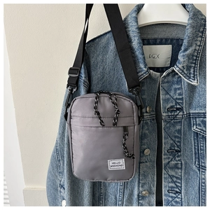 Close-up of grey Oxford crossbody bag with Hello Weekend label on denim jacket