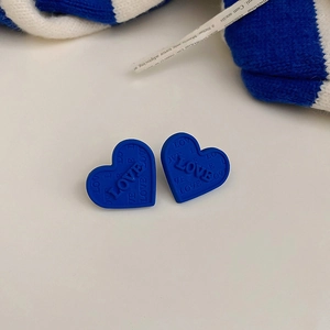 Detailed close-up of blue heart-shaped earrings featuring embossed LOVE lettering pattern