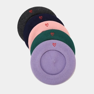 Detailed view of colorful wool berets featuring delicate red heart embroidery