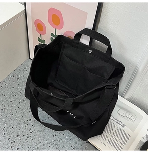 Détail intérieur du grand sac cabas noir en toile avec deux poches et bouton pression