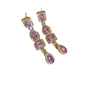 Elegant gold bow earrings with purple gemstones and tassel in a long dangle drop design
