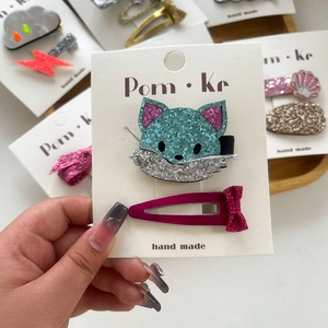 Detail of sequined cat hair clips and pink velvet bow clip on white handmade cards