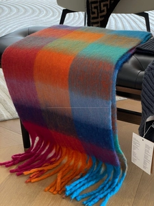 Close-up of a thick mohair scarf with vibrant plaid pattern and twisted fringe details