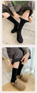 Close-up of thick black plush socks showing elastic cuff and warm fleece texture