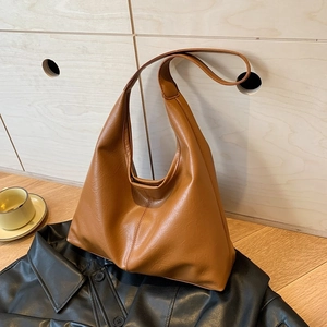 Borsa hobo vintage marrone in ecopelle con trama martellata su sfondo di pelle nera