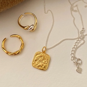 S925 sterling silver lion pendant necklace and gold twisted rings on beige background