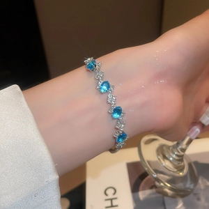 Detail of a sparkling silver bracelet with sea-blue oval zircons worn on a wrist