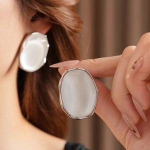 Close-up of elegant silver oval resin earrings with cat eye stone effect for women