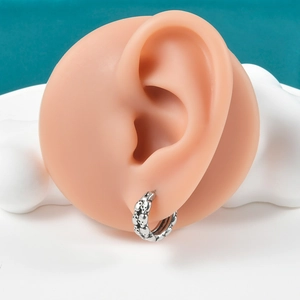 Macro detail of gothic skull hoop earring with oxidized finish on ear model