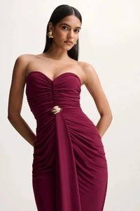 Close-up of ruched burgundy strapless dress featuring a wavy gold metal waist detail