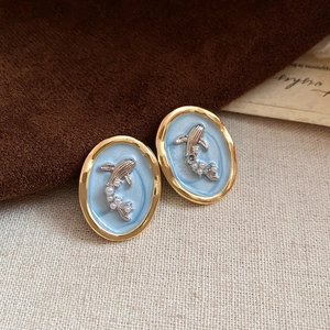 Détail de la boucle d'oreille vintage avec émail bleu, cadre doré et relief baleine perle