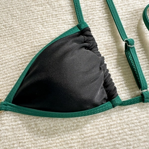 Detail of black bikini top with green trim and metal adjustment rings on the straps