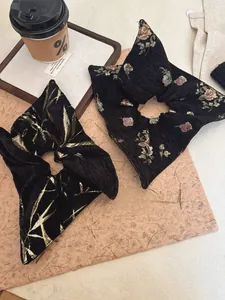 Close-up of black jacquard scrunchies with golden bamboo and floral patterns