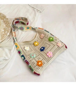 Detail view of handmade crochet tote bag with 3D floral accents and colorful strap