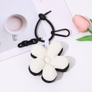 Close-up of black and white plush five-petal flower keychain with sturdy black clasp