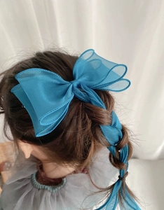 Close-up of royal blue organza layered bow hair clip on a soft braided hairstyle