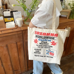 Detailed side view of the large white canvas tote bag with vintage red and black lettering