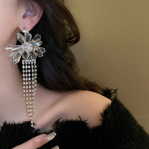 Close-up of elegant flower tassel earrings with crystals worn by a model in soft light