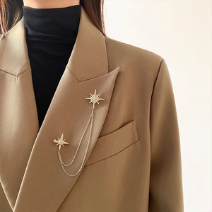 Luxury gold star brooch with double chains and rhinestones on a brown suit jacket