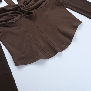 Detail of cross-twist front design and wavy hem on a dark brown crop top long sleeve