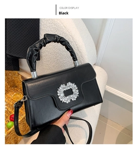 Close-up of black handbag with rhinestone buckle and stylish ruched cloud handle