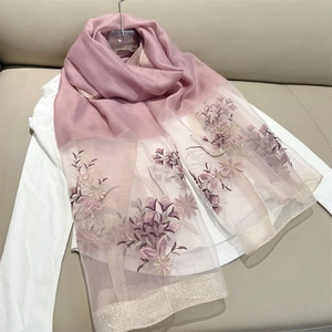 Macro detail of pink gauze scarf featuring elegant purple floral embroidery and gold accents