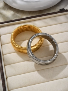 Macro detail of gold and silver Tubogas stretch bracelets in a velvet jewelry box